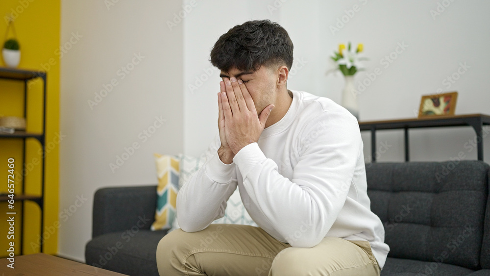 Young hispanic man stressed sitting on sofa at home Young hispanic man stressed sitting on sofa at home
