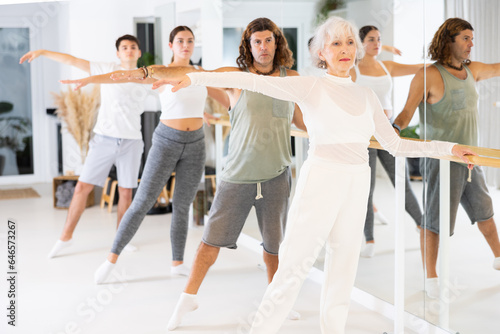 Foto Group of people of different ages practice ballet moves in classical dance school