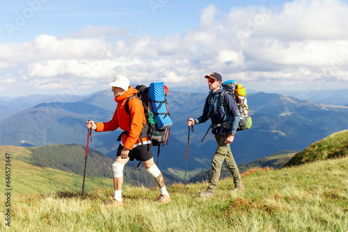 two men with hiking equipment and backpacks go to the mountains with trekking poles © Богдан Маліцький