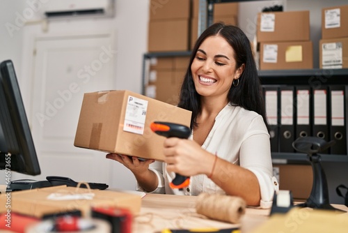 Young beautiful hispanic woman ecommerce business worker scanning package at office