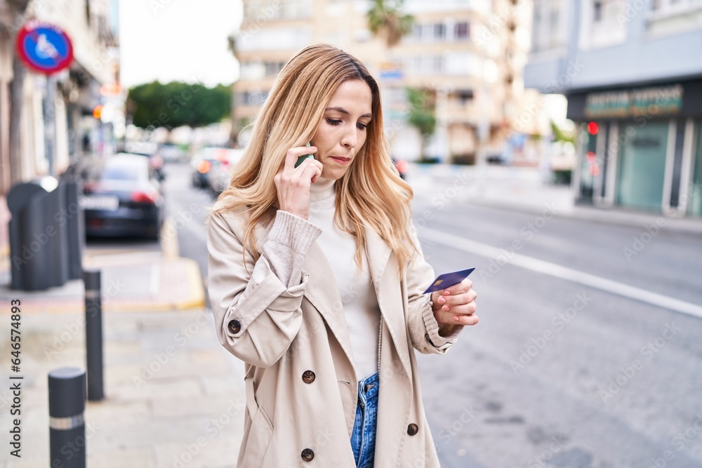 Fototapeta premium Young blonde woman using smartphone and credit card at street