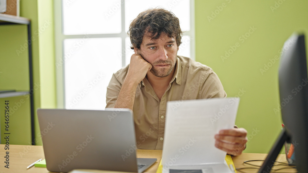 Young hispanic man business worker using laptop reading document at office Young hispanic man business worker using laptop reading document at office