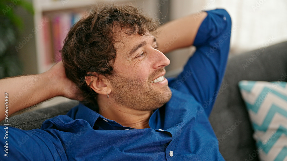 Young hispanic man relaxed with hands on head sitting on sofa at home Young hispanic man relaxed with hands on head sitting on sofa at home