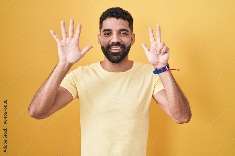 Hispanic man with beard standing over yellow background showing and pointing up with fingers number eight while smiling confident and happy. Hispanic man with beard standing over yellow background showing and pointing up with fingers number eight while smiling confident and happy.