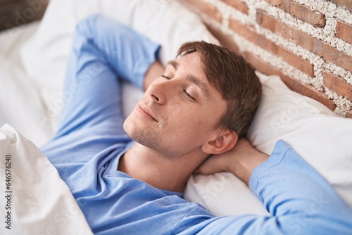 Young caucasian man lying on bed sleeping at bedroom