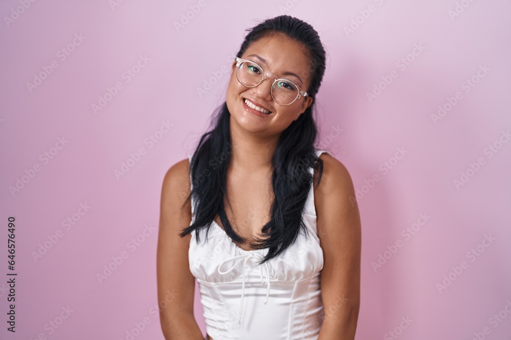Asian young woman standing over pink background looking positive and happy standing and smiling with a confident smile showing teeth Asian young woman standing over pink background looking positive and happy standing and smiling with a confident smile showing teeth