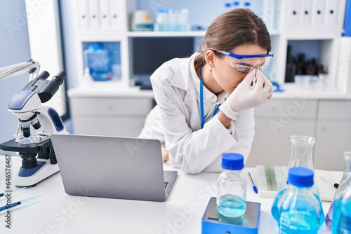 Young caucasian woman scientist stressed using laptop at laboratory