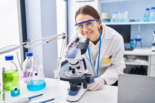 Young caucasian woman scientist using microscope at laboratory