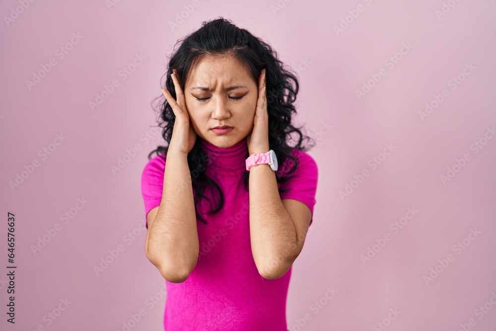 Young asian woman standing over pink background with hand on head, headache because stress. suffering migraine. Young asian woman standing over pink background with hand on head, headache because stress. suffering migraine.
