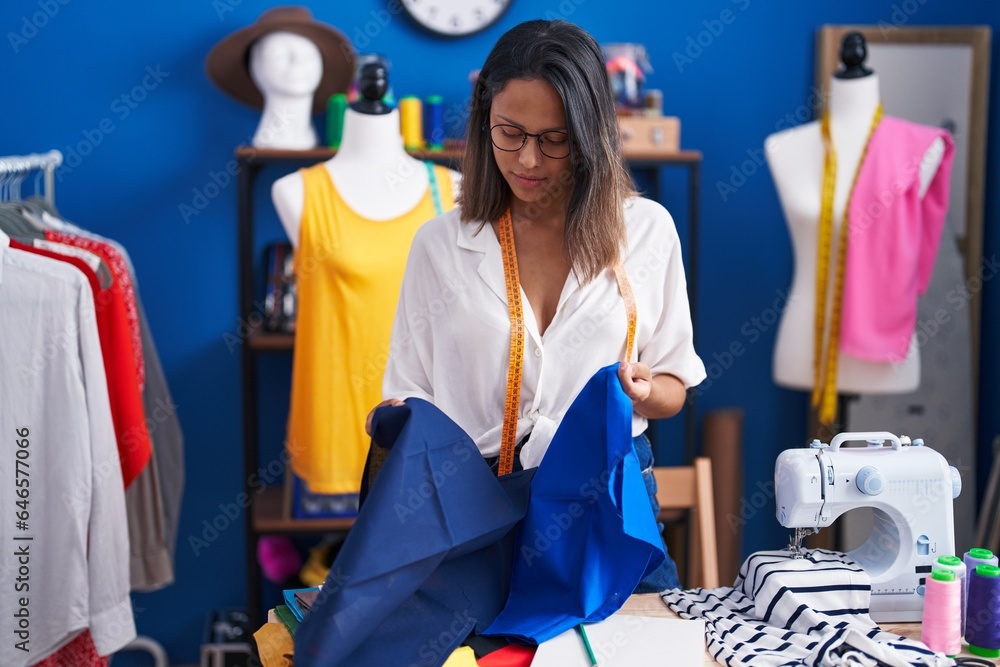 Young hispanic woman tailor holding cloth at sewing studio Young hispanic woman tailor holding cloth at sewing studio