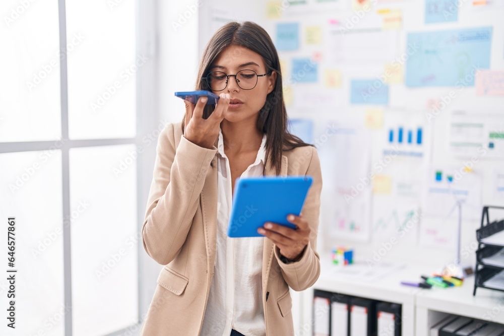 Young beautiful hispanic woman business worker talking on smartphone using touchpad at office Young beautiful hispanic woman business worker talking on smartphone using touchpad at office