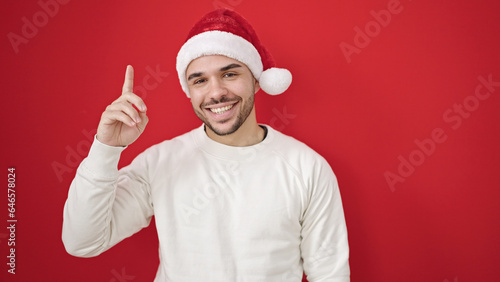 Young hispanic man wearing christmas hat having idea over isolated red background