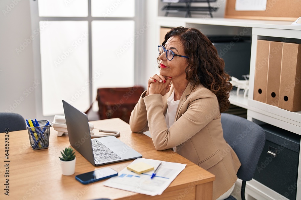 Middle age hispanic woman working with laptop at the office Middle age hispanic woman working with laptop at the office