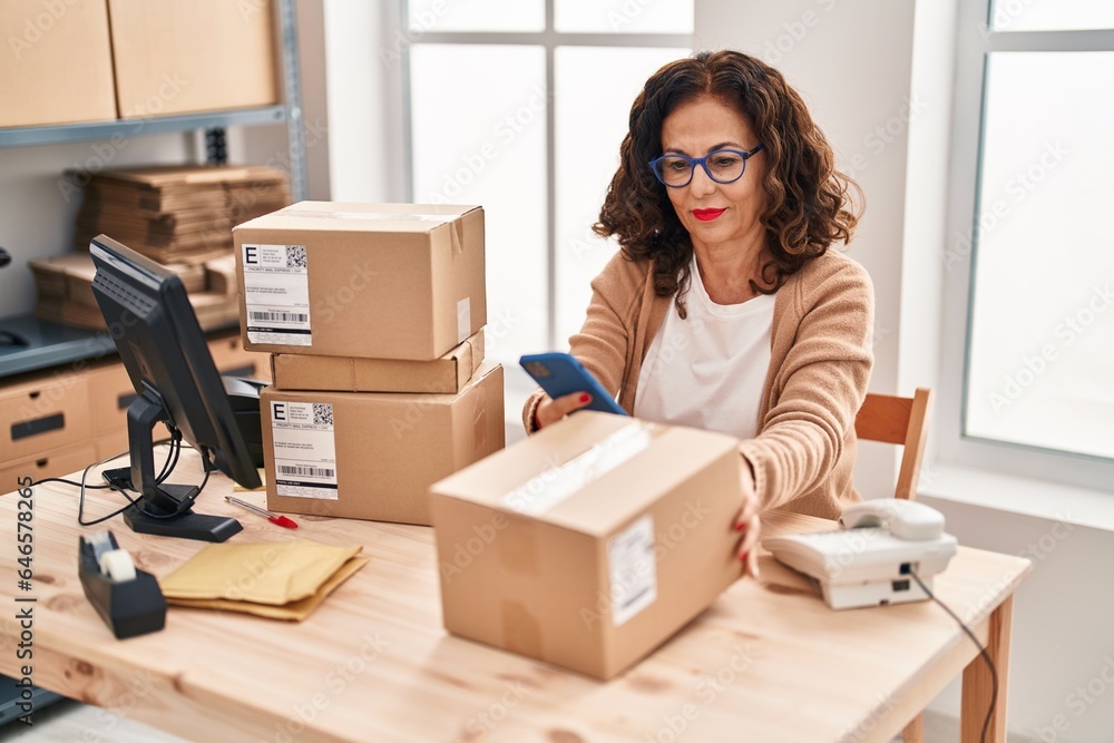 Middle age hispanic woman working with parcels at ecommerce Middle age hispanic woman working with parcels at ecommerce