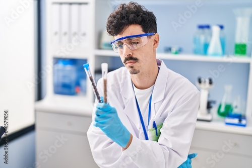 Young caucasian man scientist holding test tubes at laboratory