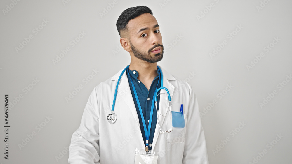 Young hispanic man doctor standing with serious expression over isolated white background Young hispanic man doctor standing with serious expression over isolated white background