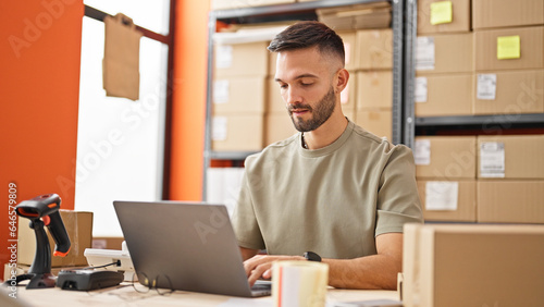 Young hispanic man ecommerce business worker using laptop at office