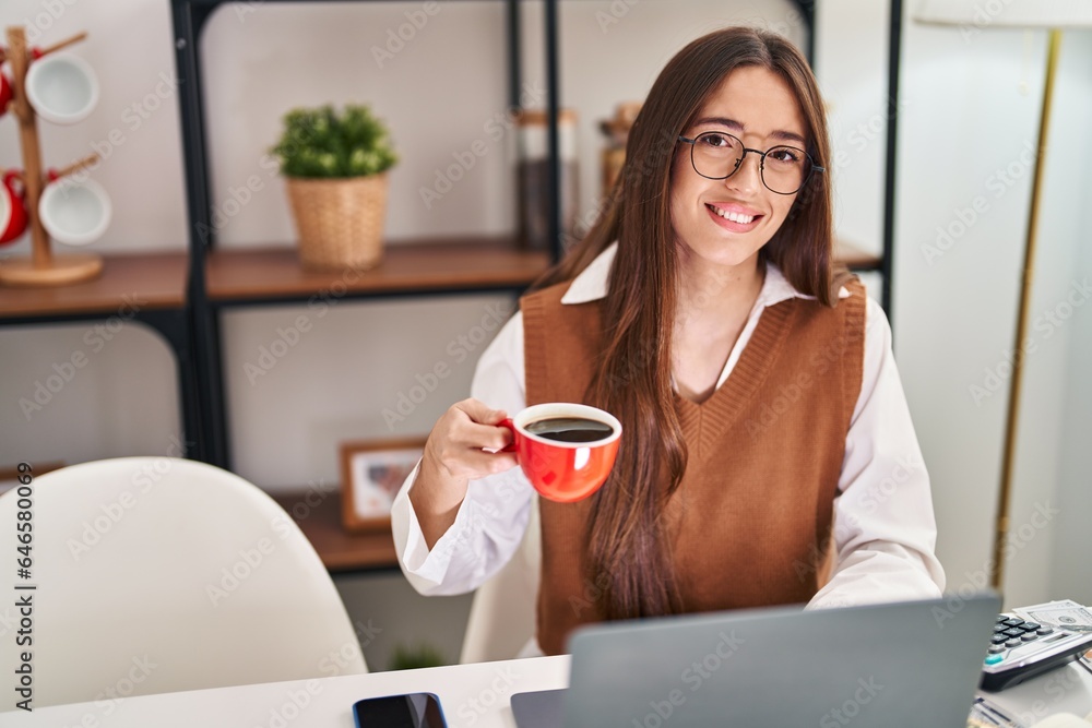 Young beautiful hispanic woman using laptop drinking coffee at home