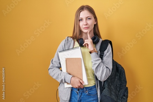 Young caucasian woman wearing student backpack and holding books thinking concentrated about doubt with finger on chin and looking up wondering © Krakenimages.com
