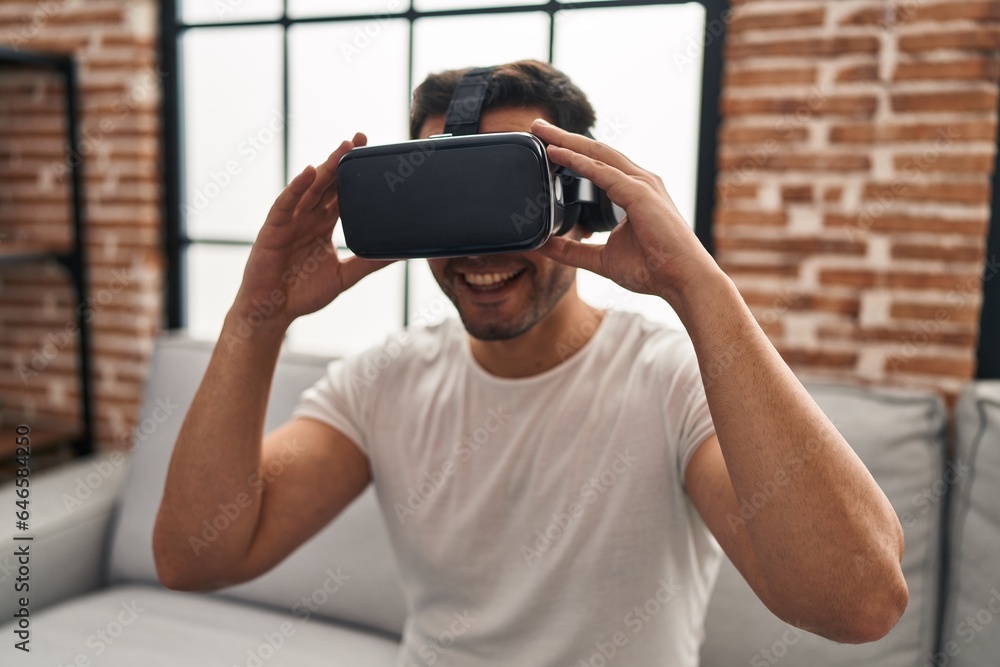 Young hispanic man playing video game using virtual reality glasses at home Young hispanic man playing video game using virtual reality glasses at home