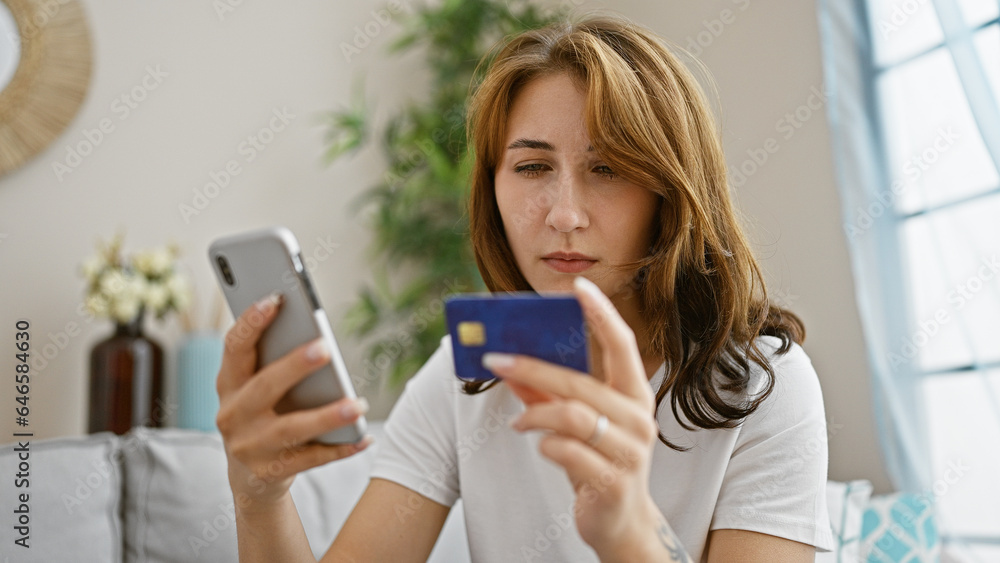 Young woman shopping with smartphone and credit card sitting on sofa at home Young woman shopping with smartphone and credit card sitting on sofa at home