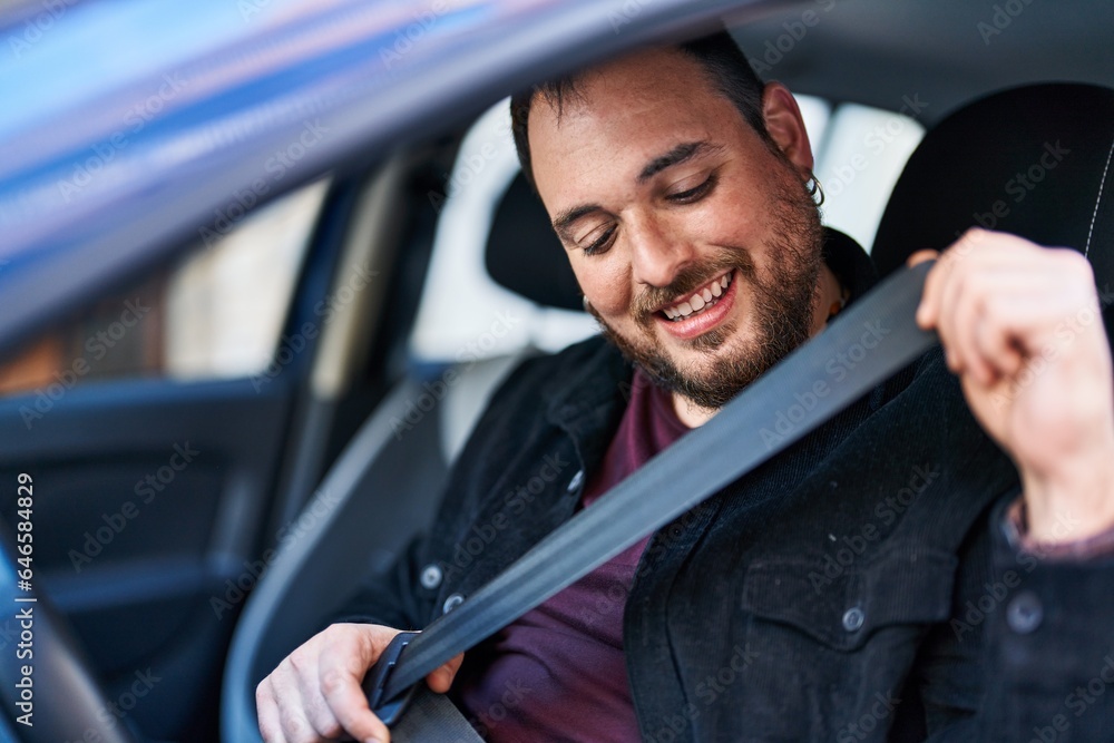 Young hispanic man wearing belt sitting on car at street Young hispanic man wearing belt sitting on car at street