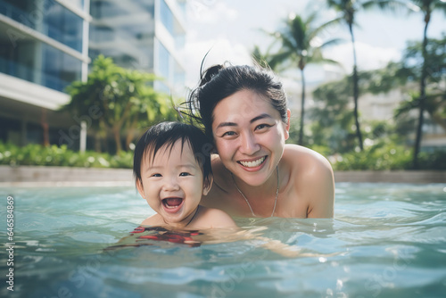 Asian mother and her baby are swimming in a pool, smiling, lifestyle photoshoot