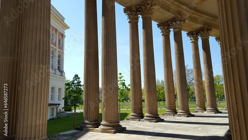 A row of pillars in front of a building, standing tall and strong, supporting the structure with grace and elegance..