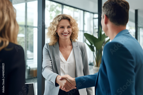 Wallpaper Mural Happy middle aged business woman meets its client and shakes hands in a modern office. Smiling female executive manager shaking hands with client after making successful deal with partner Torontodigital.ca