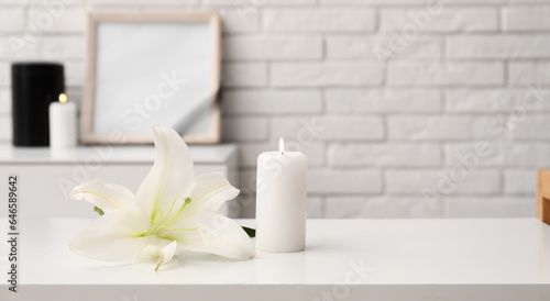 Glowing candle and lily flower on table in room