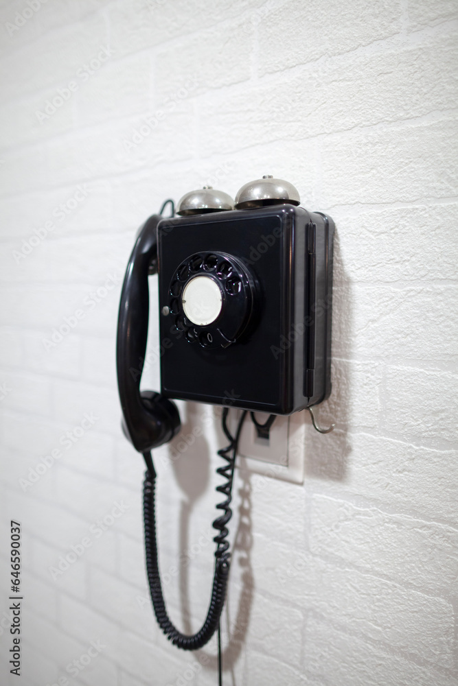 Old black telephone on a white wall. The concept of technology changeability.
