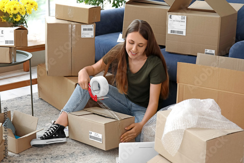 Young woman taping parcel f...