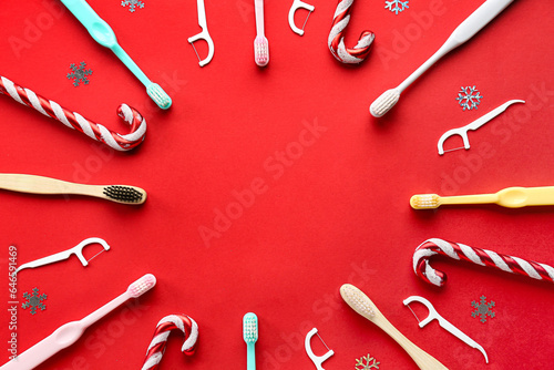 Frame made of toothbrushes with floss and Christmas decor on red background