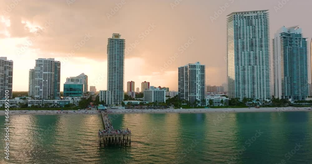 Newport Fishing Pier in Sunny Isles Beach city with waterfront highrise hotels and condo buildings on Atlantic ocean shore. American tourism infrastructure in coastal southern Florida Newport Fishing Pier in Sunny Isles Beach city with waterfront highrise hotels and condo buildings on Atlantic ocean shore. American tourism infrastructure in coastal southern Florida