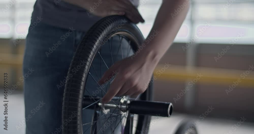 Crop male BMX rider checking tire of rear wheel Crop male BMX rider checking tire of rear wheel