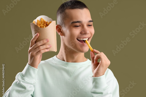 Young man eating french fri...