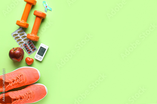 Glucometer with pills, apple, dumbbells and sneakers on green background. Diabetes concept