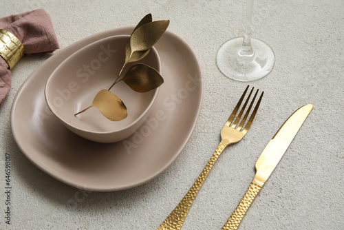 Elegant table setting with golden leaves and cutlery on grey table