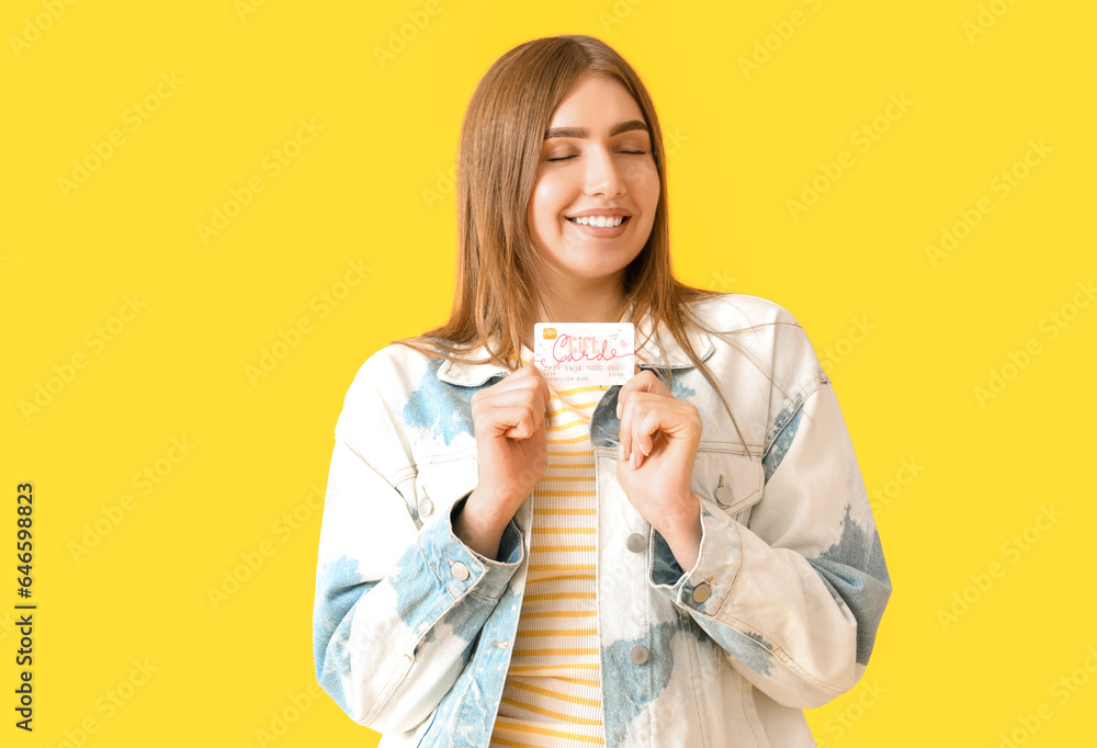 Young woman with credit card on yellow background Young woman with credit card on yellow background