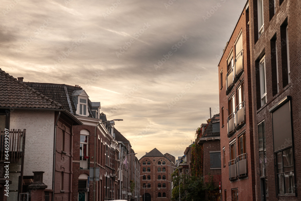 Modern residential buildings and flats in the city suburbs of Maastricht, Netherlands of red brick, in an modern street with residential buildings. It's a typical Dutch street at dusk.