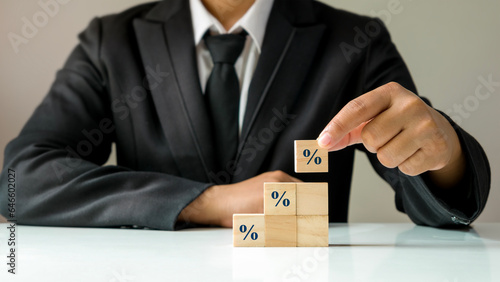 The businessman's hands place a wooden cube block with a percentage symbol icon. financial interest rate concept, rating, and mortgage rates.