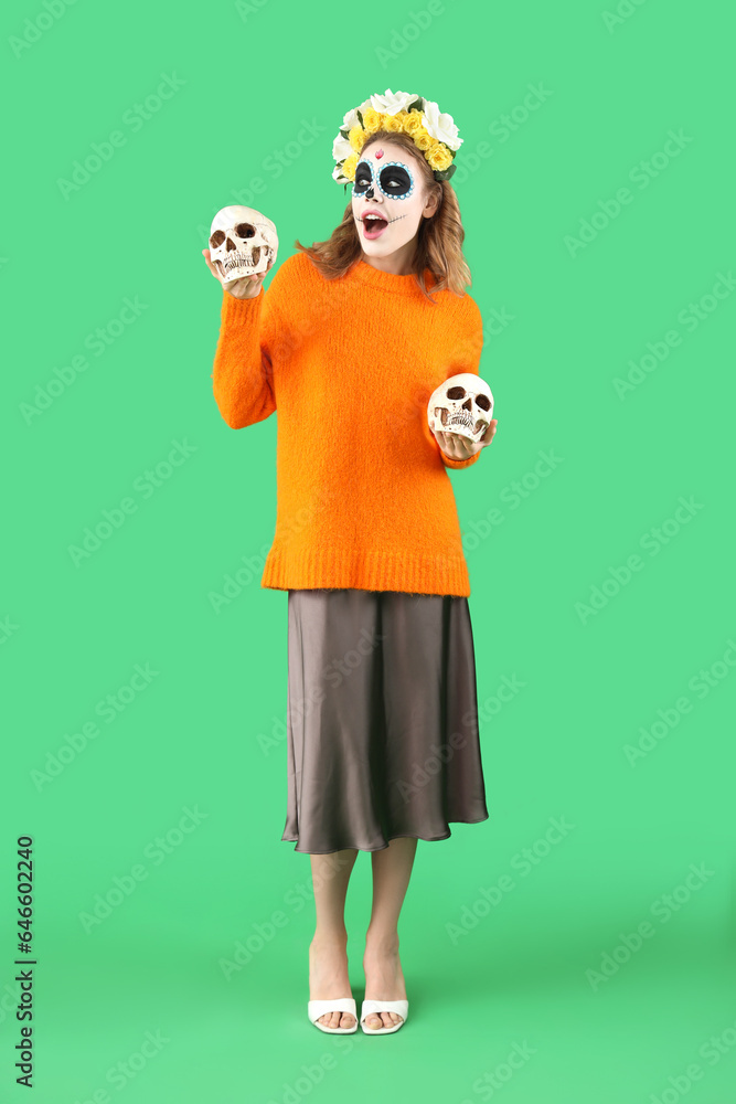 Young woman with painted skulls on green background. Mexico's Day of the Dead (El Dia de Muertos) celebration