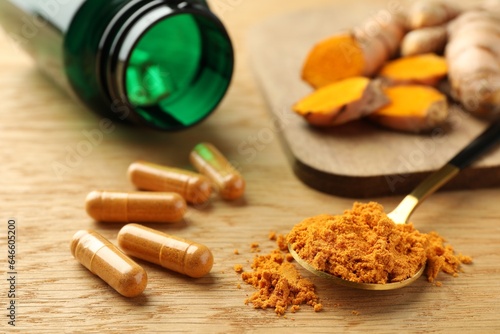 Aromatic turmeric powder and pills on wooden table, closeup
