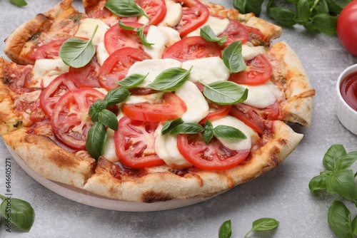 Delicious Caprese pizza with tomatoes, mozzarella and basil on light grey table, closeup