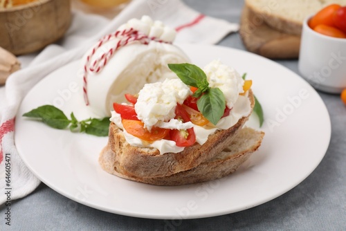 Delicious sandwich with burrata cheese and tomatoes on grey table, closeup