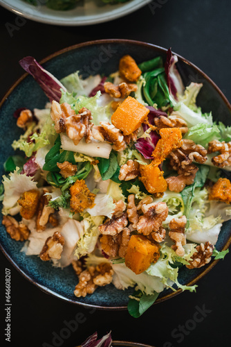 Top view of fresh and vegan salad with lettuce, pumpkin, walnut, rocket leaves. Brunch concept.