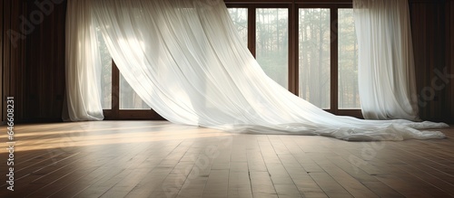 The wind moves a white curtain, revealing the wooden floor.