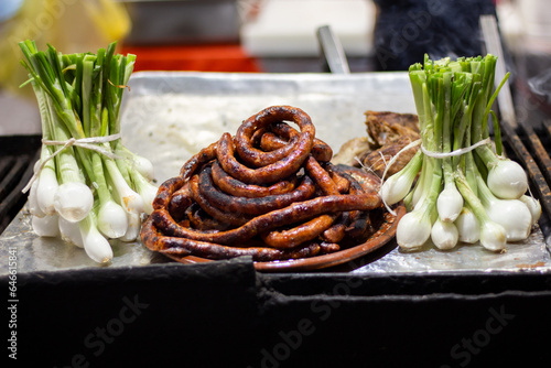 Chorizo o longaniza asada y cebollitas cambray en la parrilla de una taquería en México photo