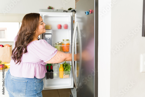Latin woman looking for food opening the fridge