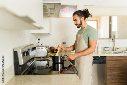 Young man cooking pasta in the electric stove top
